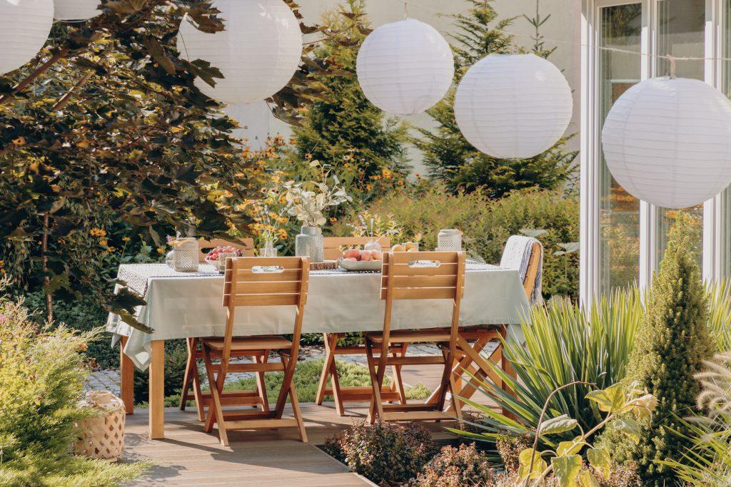 Round lamps above a table with wooden chairs in a garden